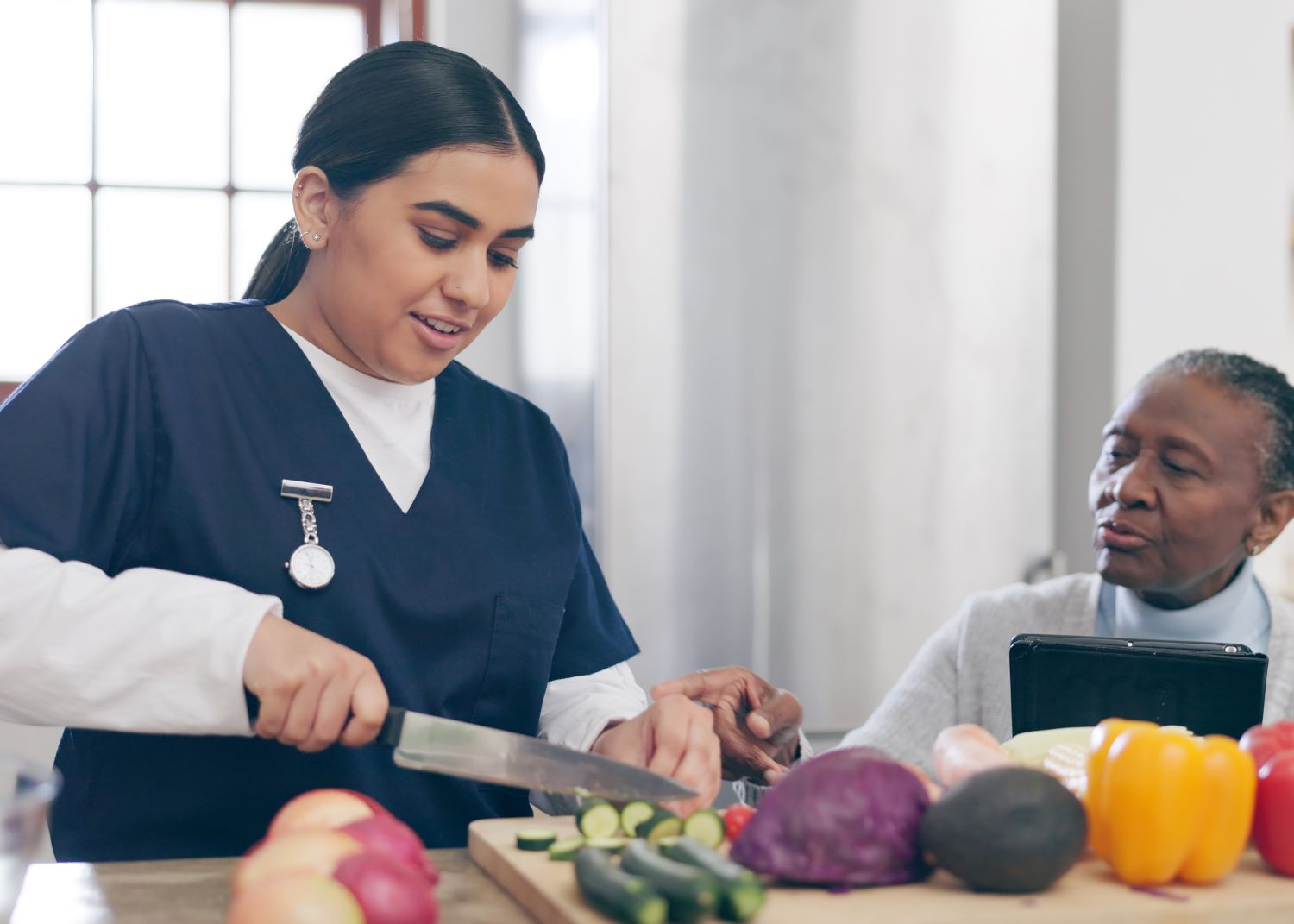 Caregiver preparing a healthy home-cooked meal alongside a senior client in their kitchen