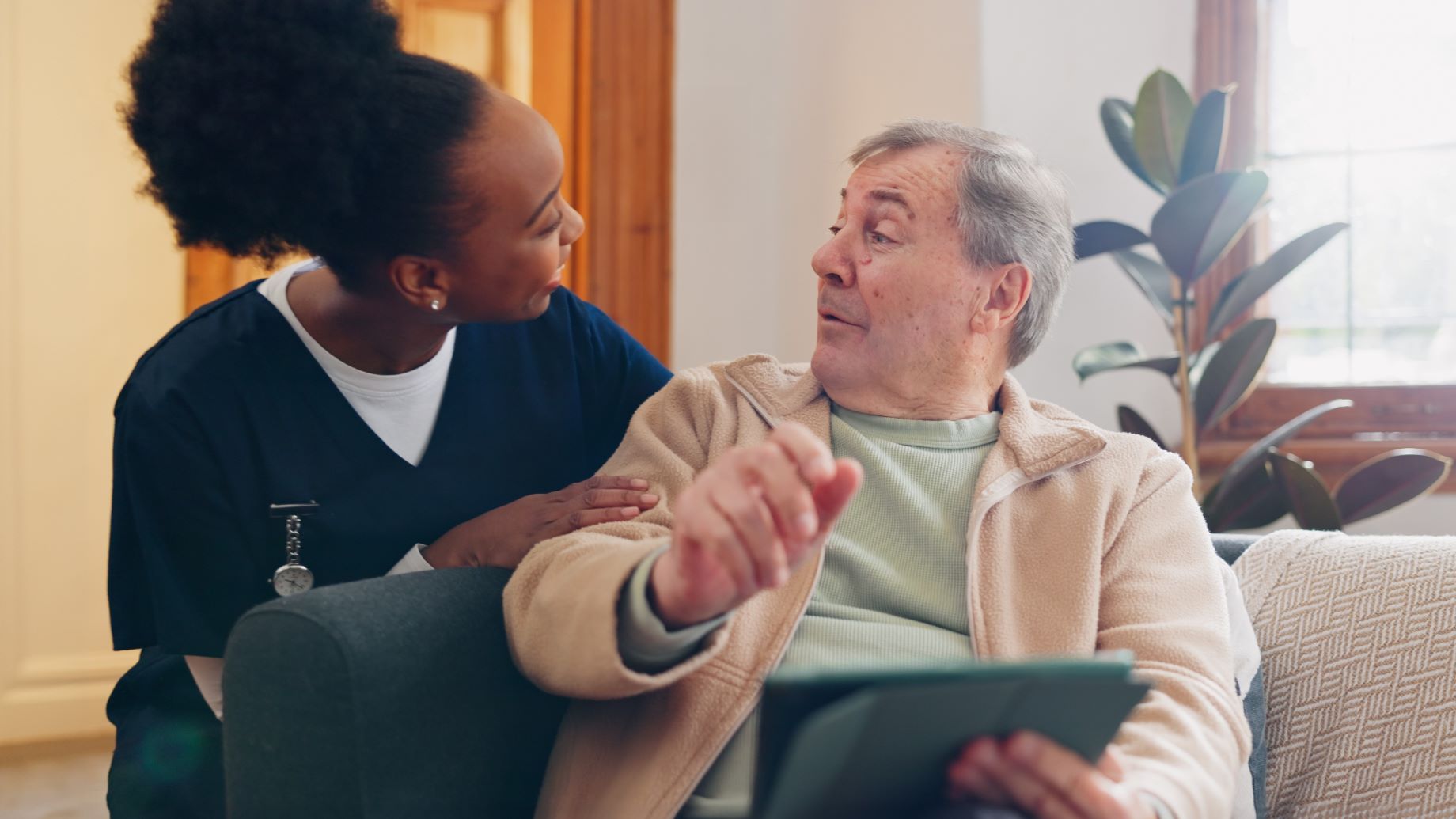Caregiver using a tablet to access Greys Home Care employee resources and tools