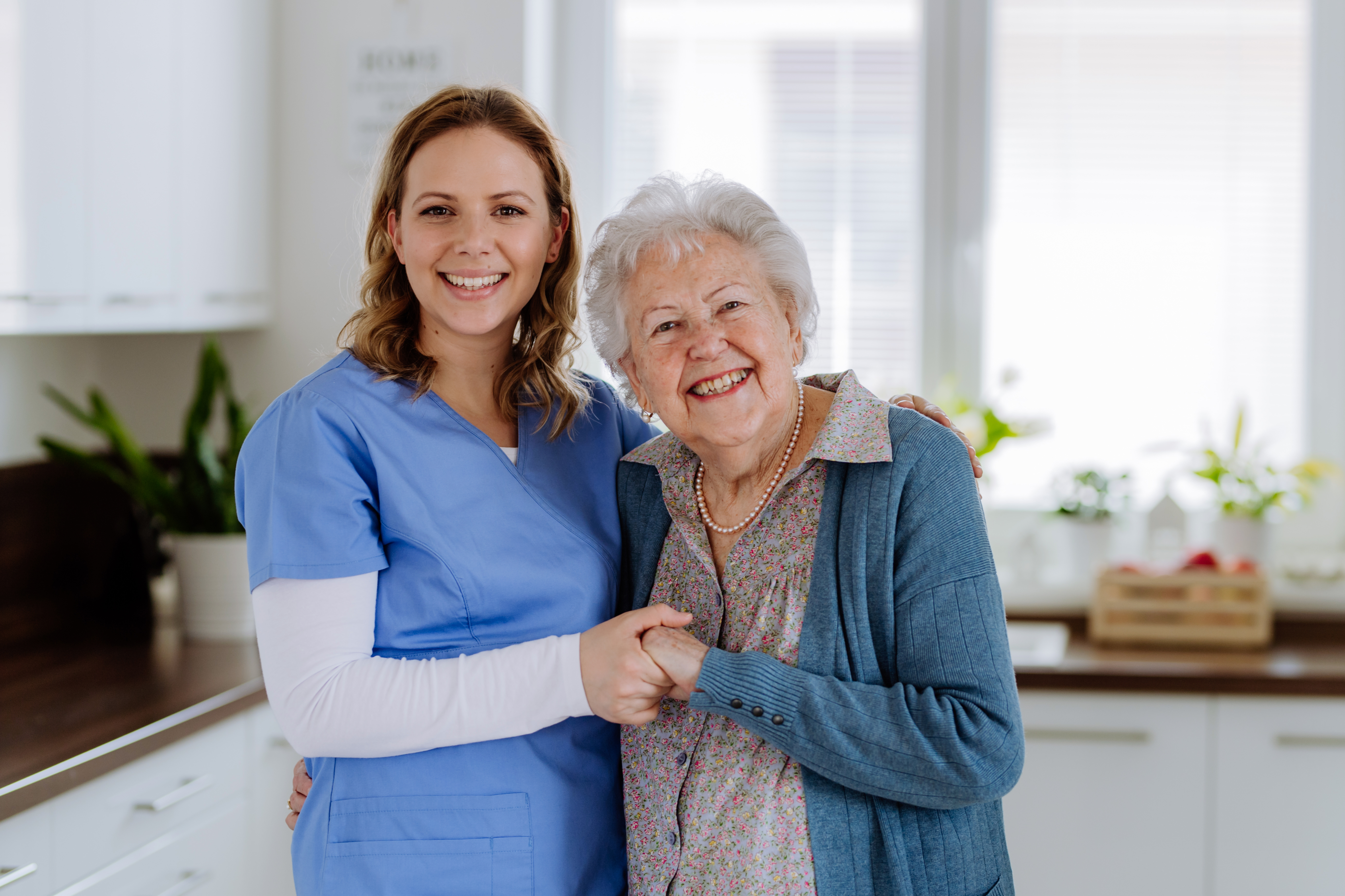 A caring Greys Home Care caregiver embraces her senior client in a warm, sunlit Connecticut home